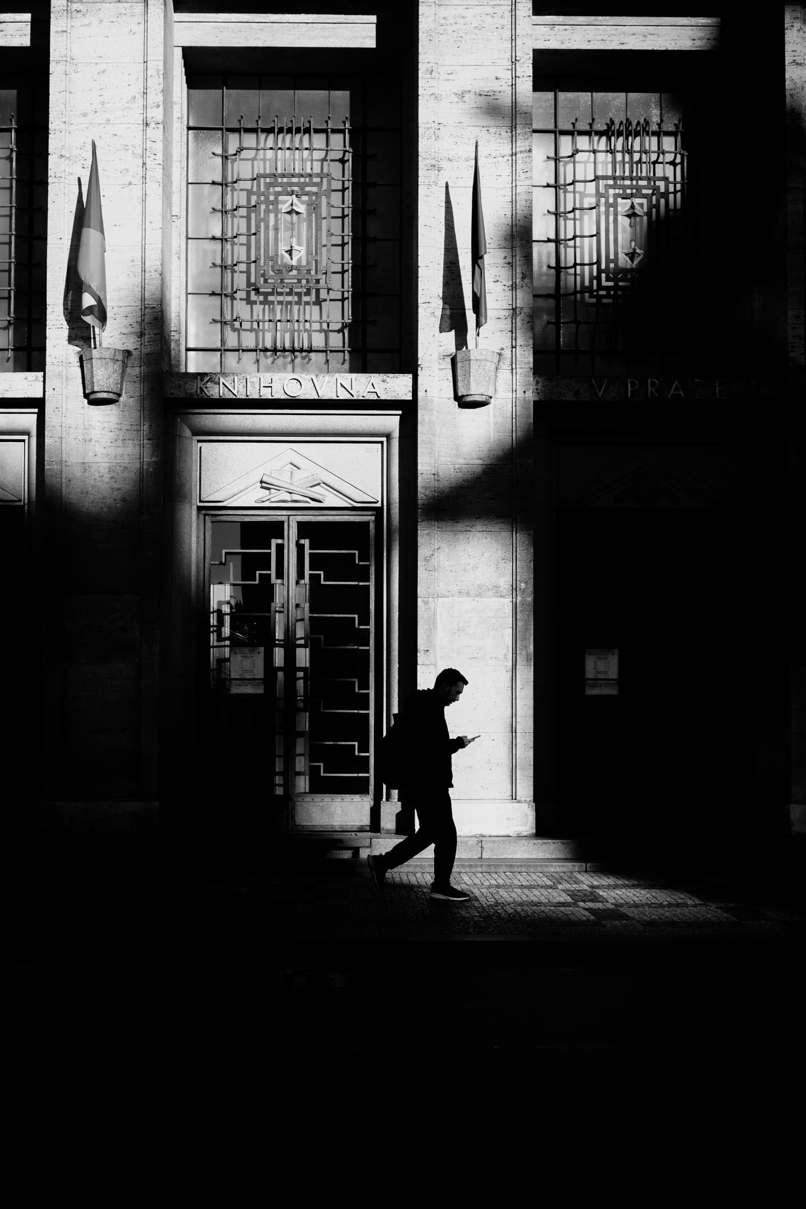 A man walks past the Prague City Library through a band of hard light