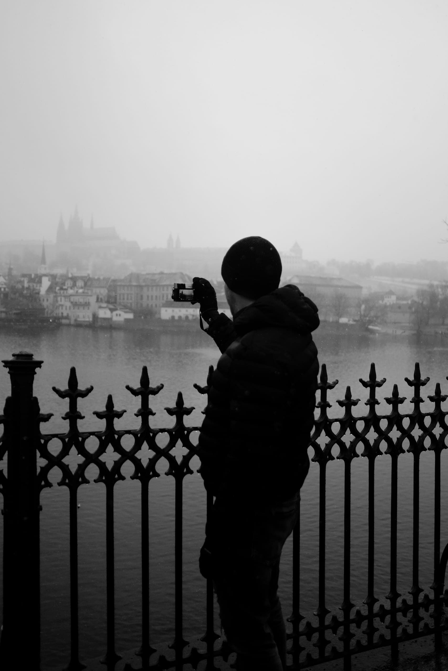A workshop photographer at the river railing, photographing Prague Castle through the fog